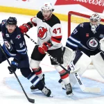 Jan 11, 2026; Winnipeg, Manitoba, CAN; Winnipeg Jets defenseman Dylan Samberg (54), New Jersey Devils left wing Paul Cotter (47) and Winnipeg Jets goaltender Connor Hellebuyck (37) watch a play develop during the third period at Canada Life Centre. Mandatory Credit: James Carey Lauder-Imagn Images