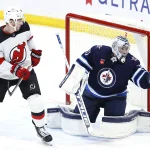 wing Nathan Bastian (14) watches Winnipeg Jets goaltender Connor Hellebuyck (37) miss a glove save in the third period at Canada Life Centre.