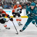 Dec 31, 2024; San Jose, California, USA; San Jose Sharks center Macklin Celebrini (71) shoots the puck against Philadelphia Flyers right wing Travis Konecny (11) and right wing Owen Tippett (74) during the second period at SAP Center at San Jose.